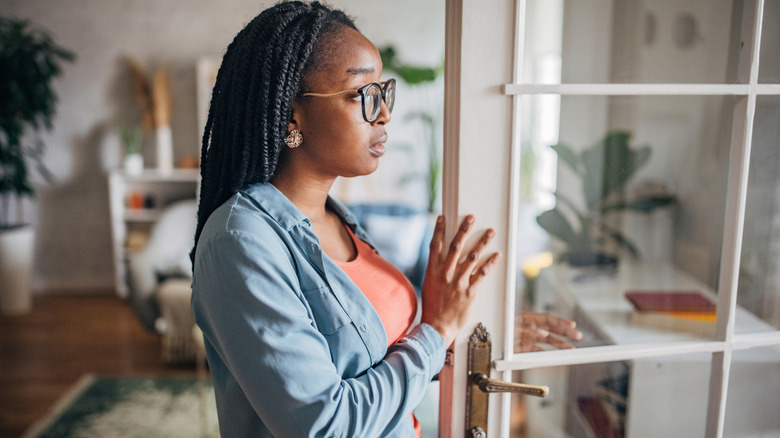 A woman is deep in thought while opening a door