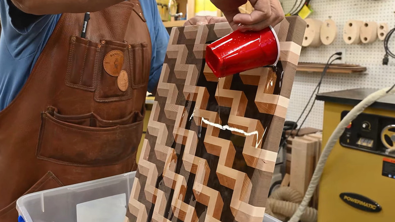 A man pouring mineral oil over a cutting board