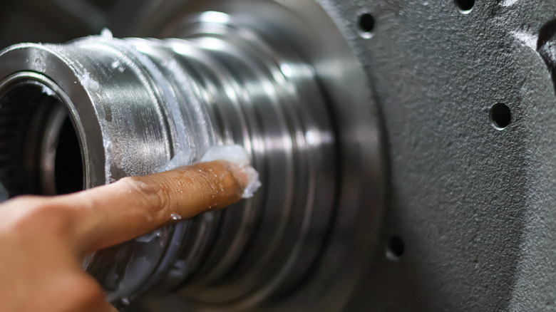 A person applying petroleum jelly to machinery