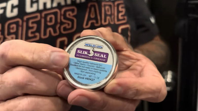 A man holding a tin of plumber's grease