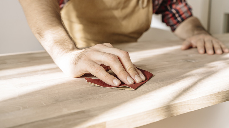 A person sanding a piece of wood
