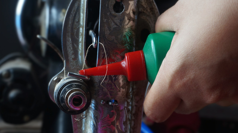 A person dripping sewing machine oil into machinery