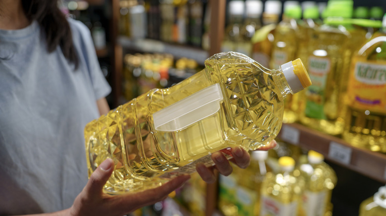 A shopper holding a bottle of vegetable oil
