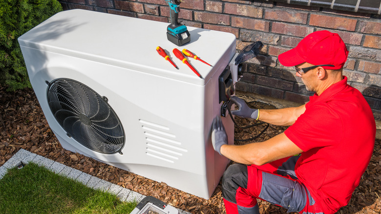 An HVAC technician works on an outdoor unit