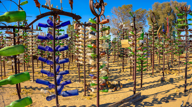 Metals trees with an assortment of colorful glass bottles on them