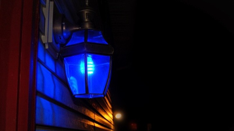 A porch lantern glowing a dark blue color at night
