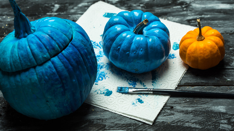 A paintbrush next to pumpkins painted blue