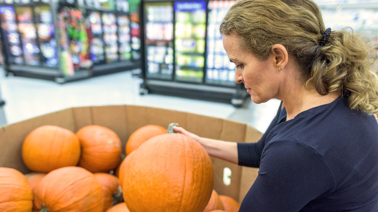 Woman looking at pumpkins for sale at supermarket