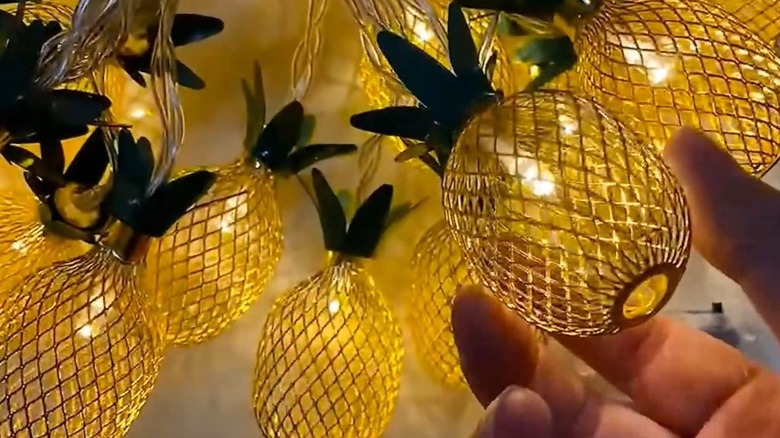 A hand holding a strand of pineapple string lights