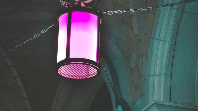 A pink decorative lantern hanging from heavy chains