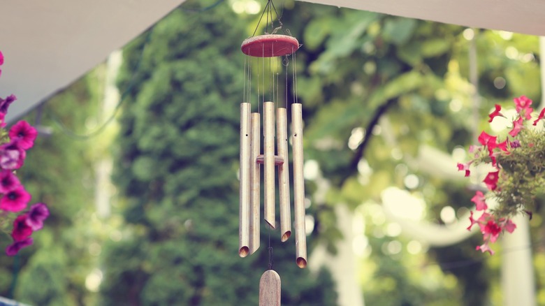 Wind chime hanging on porch next to red flowers