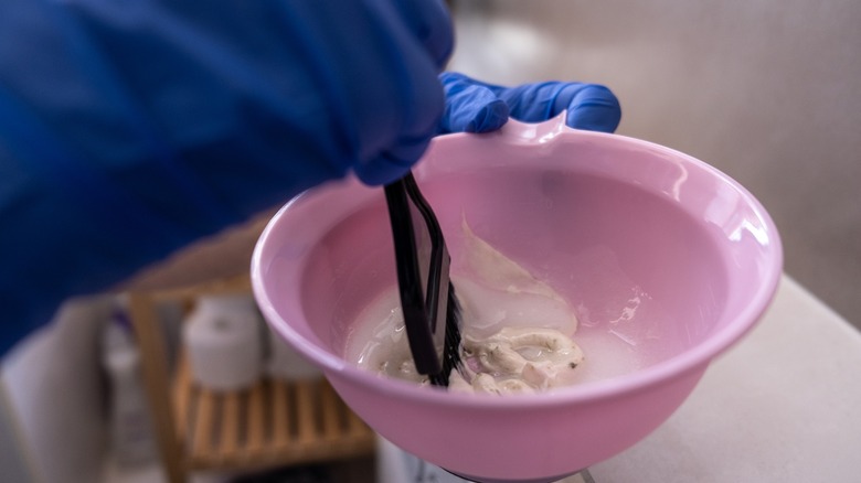 Person wearing gloves mixing a cleaning paste in a bowl