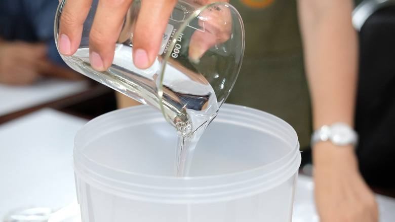 Person pouring hydrogen peroxide into container