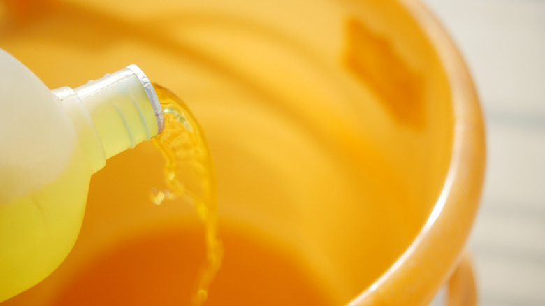 Pouring a clear liquid in an orange bucket