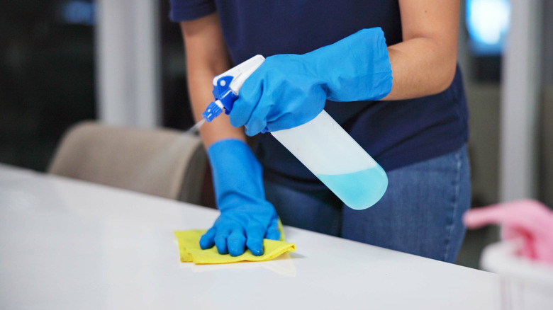 Person spraying cleaning solution on counter