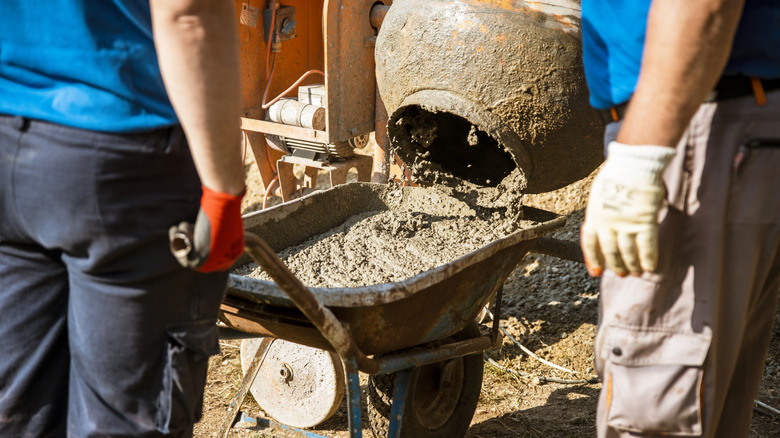 Pouring concrete from mixer into wheelbarrow