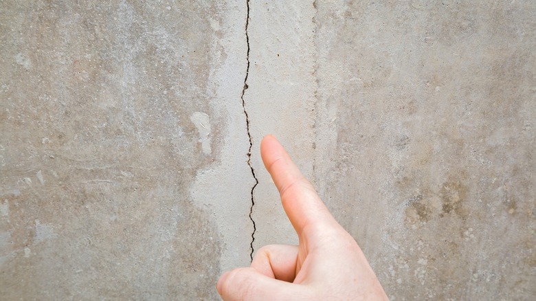 Finger pointing to crack in concrete surface