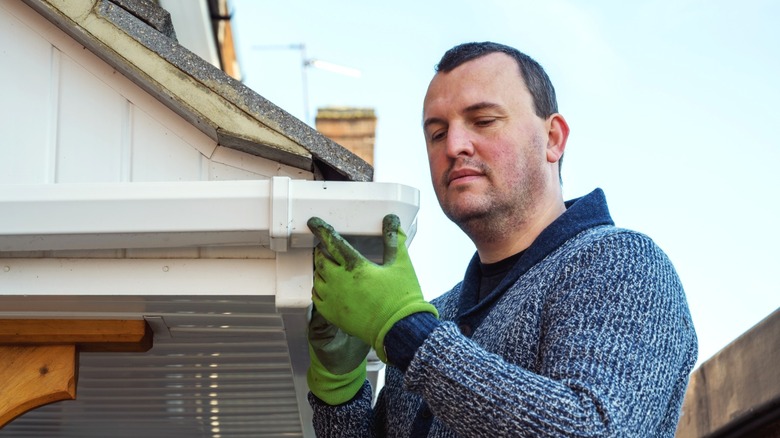 man inspecting a clogged house gutter