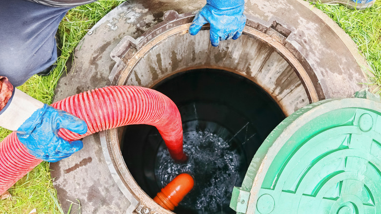 A person using a hose and pump to clean a septic tank