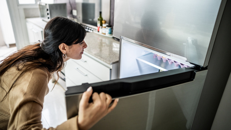 A woman opens her freezer door