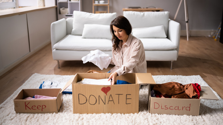 Woman placing items in different boxes while decluttering