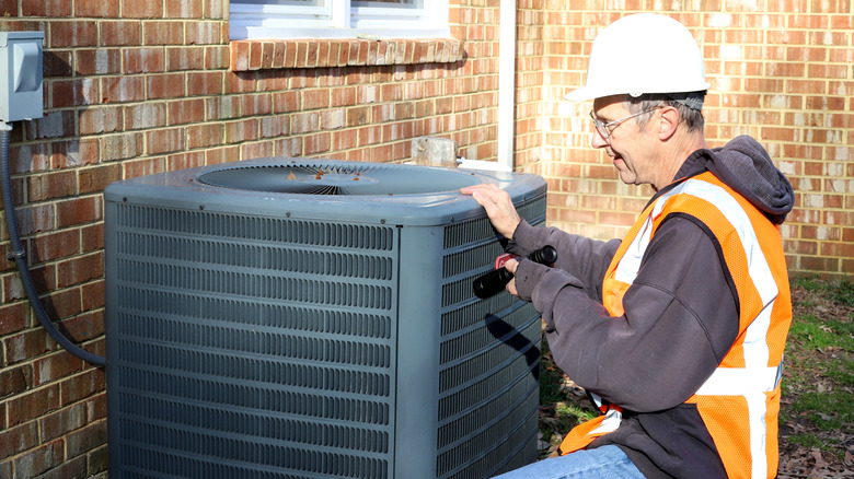 An HVAC expert looks at an outdoor unit