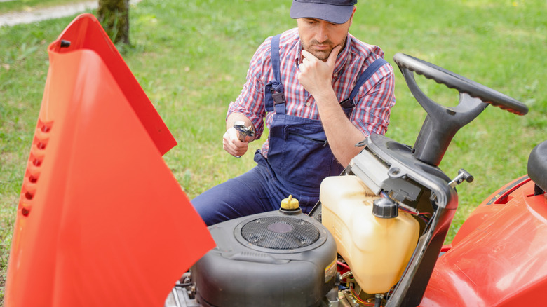 A mechanic is looking at a riding lawn mower