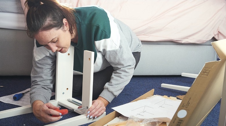 Woman assembling IKEA furniture on the floor
