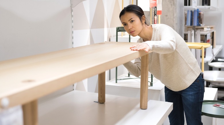 Woman inspecting a wood bench in an IKEA showroom