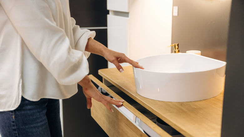 Woman opening a drawer in a bathroom vanity
