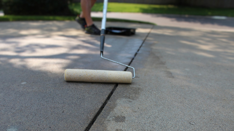 Homeowner sealing concrete driveway