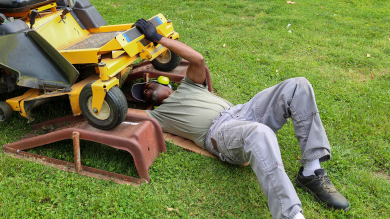 Man repairing a riding lawn mower