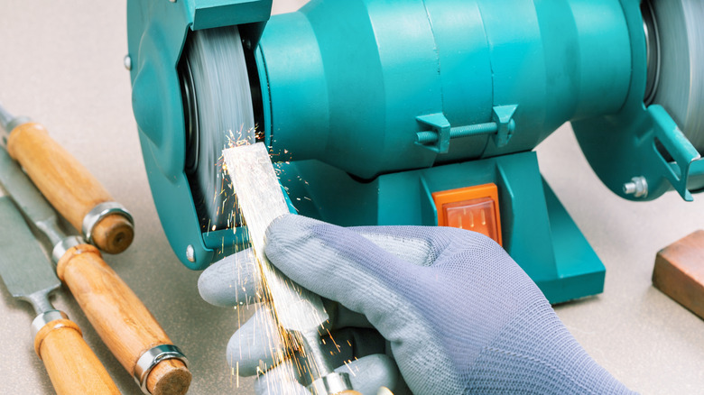 a bench grinder sending vertical sparks on sharpening blade