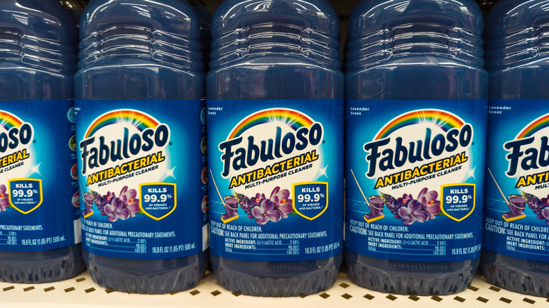 a shelf lined with bottles of Fabuloso Antibacterial Multi-Purpose Cleaner