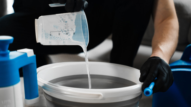 a person pours cleaner into a bucket