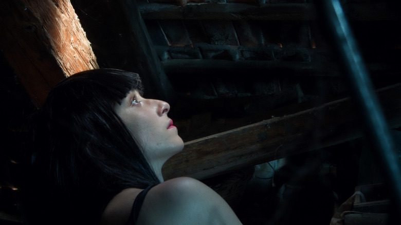 A young woman looks worried in an old attic