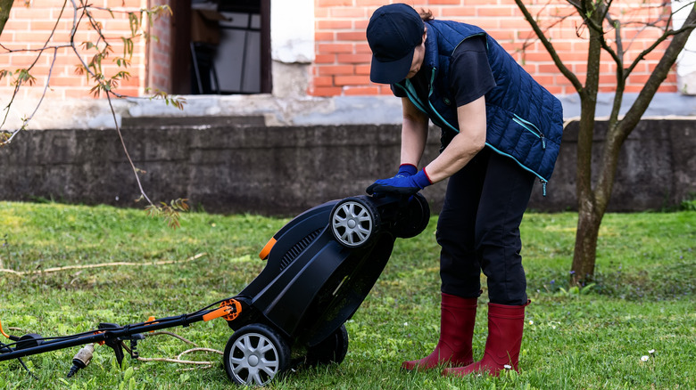 Woman looking at wheels of lawn mower