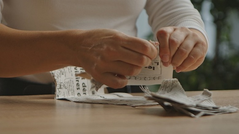 A close up of someone tearing newspaper