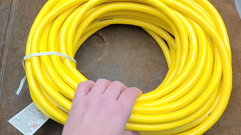 Person grabbing a wrapped-up yellow extension cord