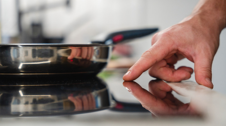 Closeup on hands turning on an induction stove