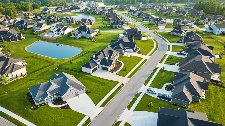 Aerial view of a new suburban neighborhood with large houses and grassy yards, many unfenced.