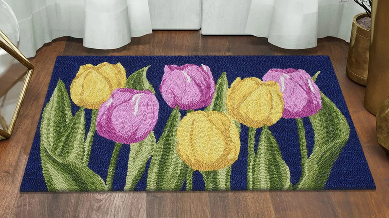 A navy blue rug with yellow and purple tulips on a hardwood floor