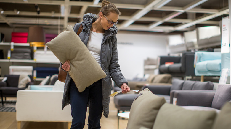 Woman wearing glasses and grey windbreaker looking at the price of a sofa for sale