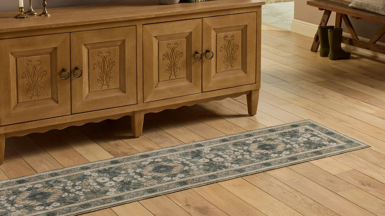 A floral-print runner rug laying in front of a credenza on a hardwood floor