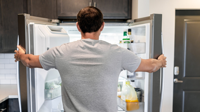 A person holding French-door fridge open