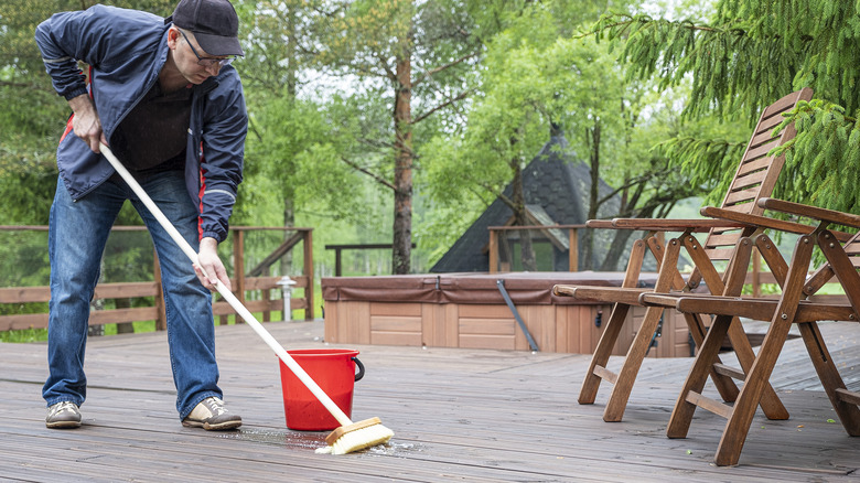 Man brushing a wood deck clean