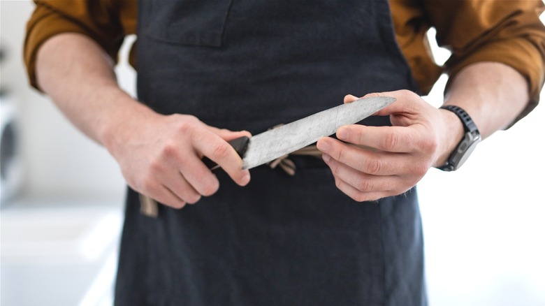 Man in the kitchen feeling the sharpness of his knife