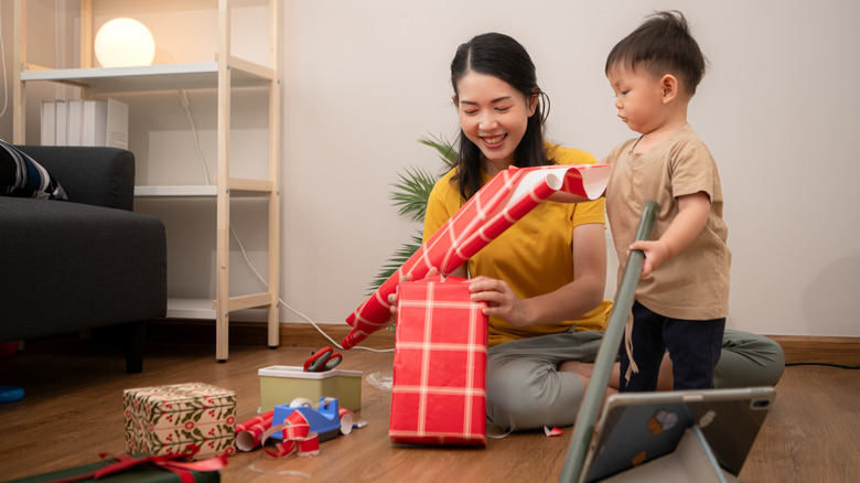 woman frustrated wrapping a stack of presents with traditional gift wrap