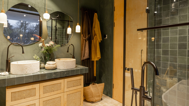 Bathroom with dark green tiles and wall and wooden accents