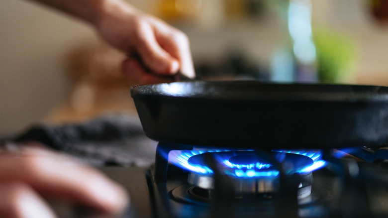 A close up of a pan on a gas stove with the flame burning blue.